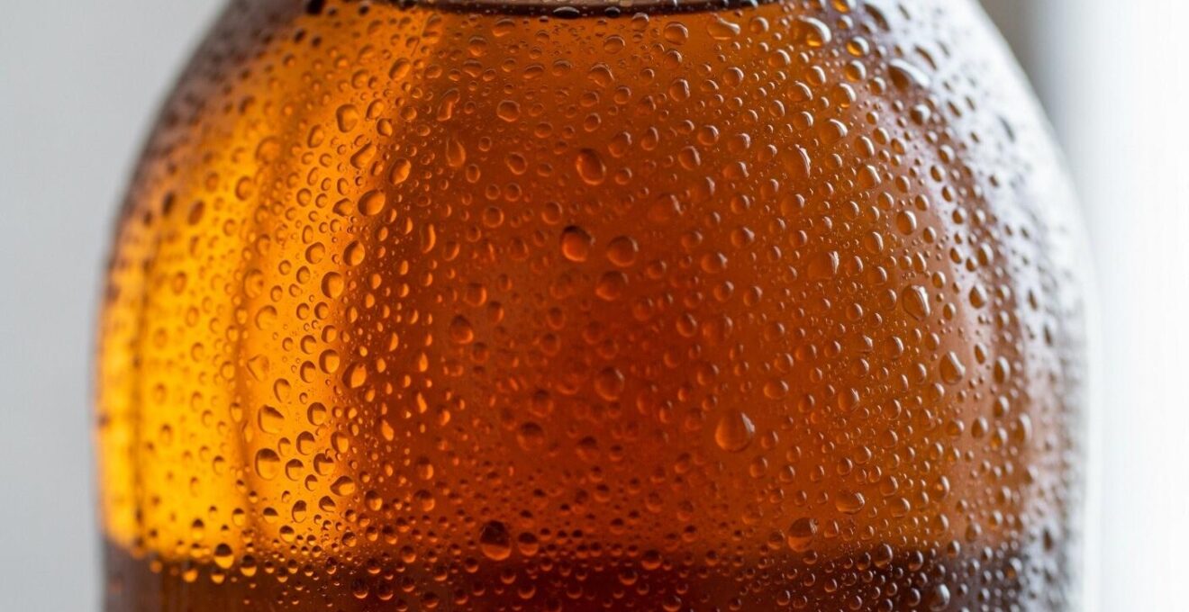 Détail macro d'une bouteille de cidre de glace avec condensation suggérant la fraîcheur et la pureté