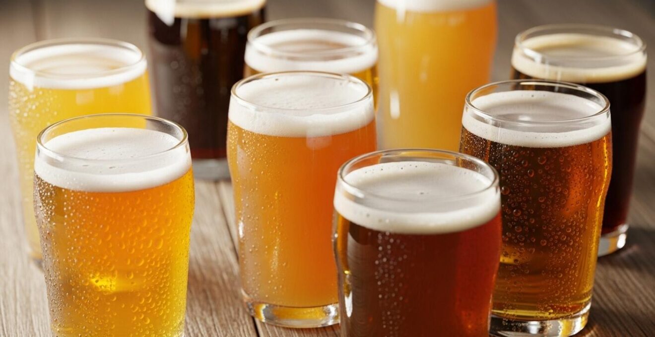 Photographie macro d’un assortiment de verres de bières IPA et NEIPA avec différentes couleurs sur une table en bois rustique